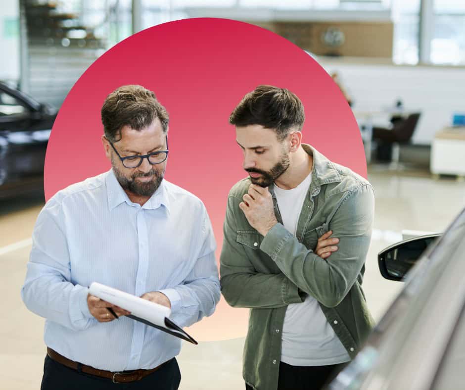 A man talks to a finance officer at a car dealership.