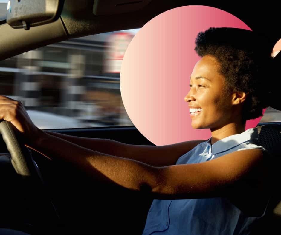 A young woman smiles as she's driving.