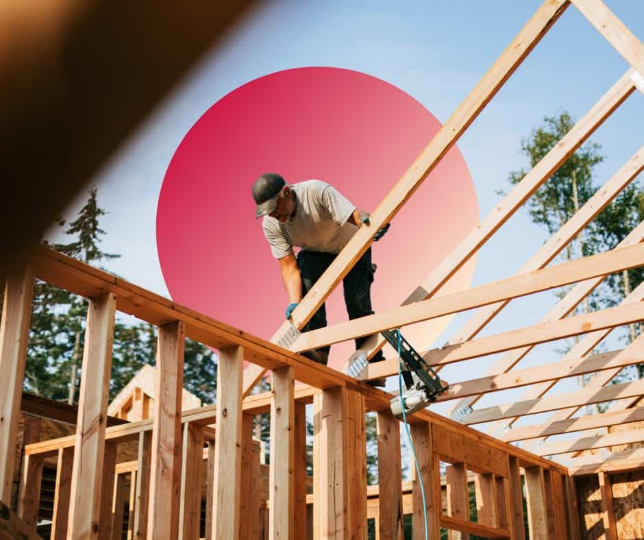 A man balancing on beams during a home construction project.