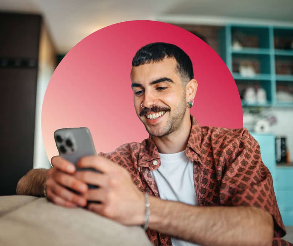 A hipster man smiling while using his cellphone.