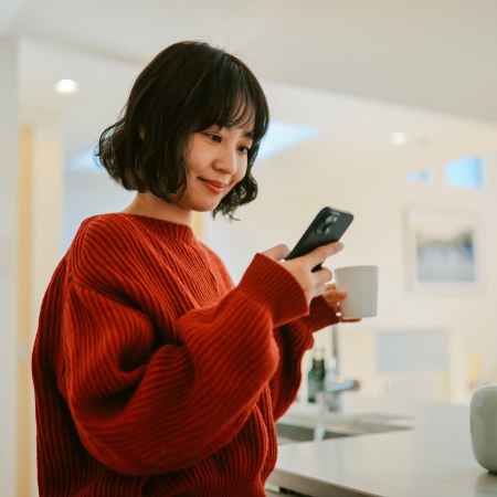 A young Asian woman smiles at her cell phone.