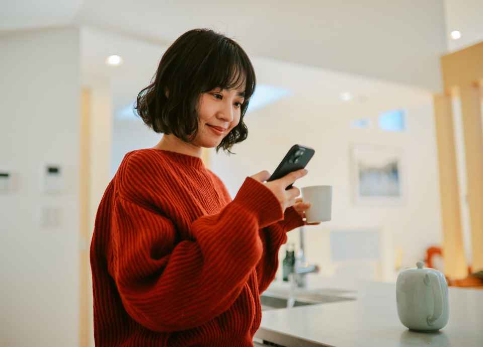 A young Asian woman smiles at her cell phone.