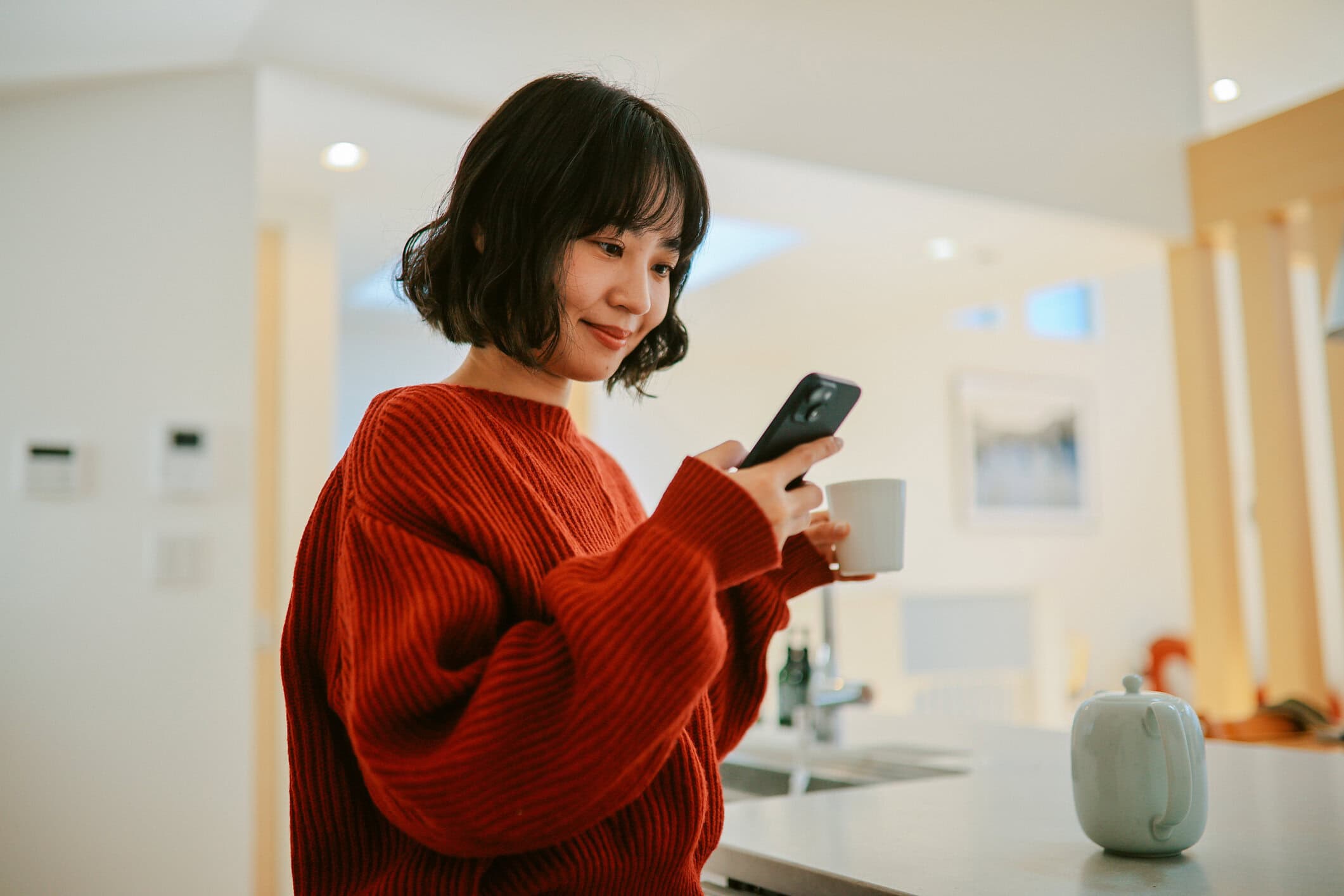 A young Asian woman smiles at her cell phone.