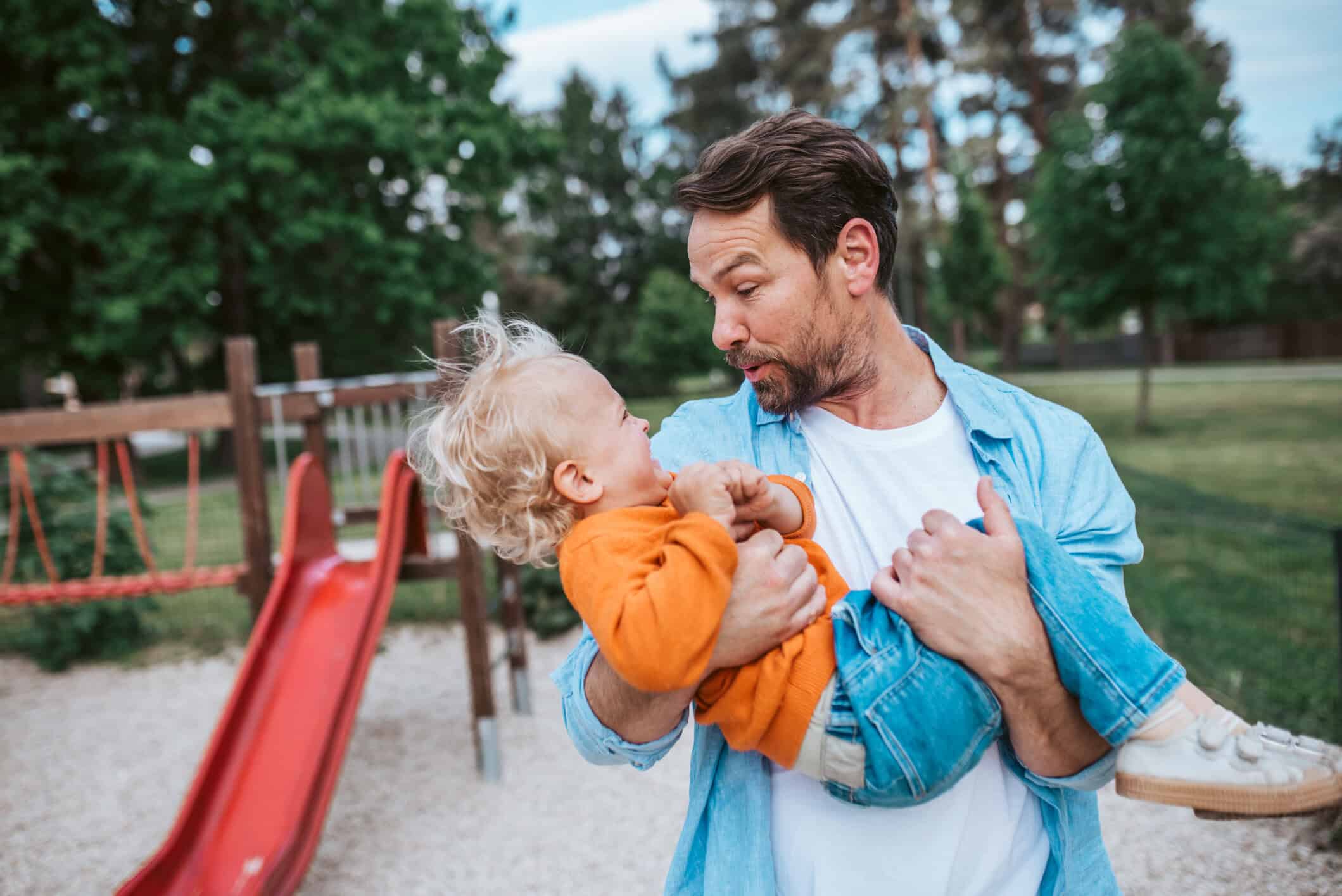 A young father plays with his child in a playground.