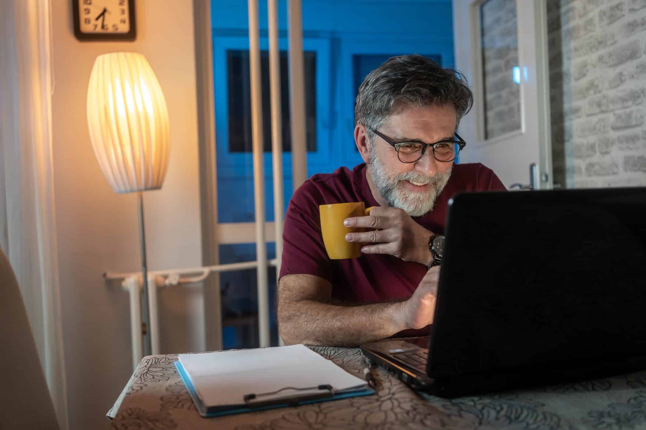An older man smiles while reading an email.