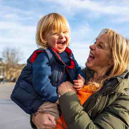 A smiling Grandmother holding her grandson on a sunny day.