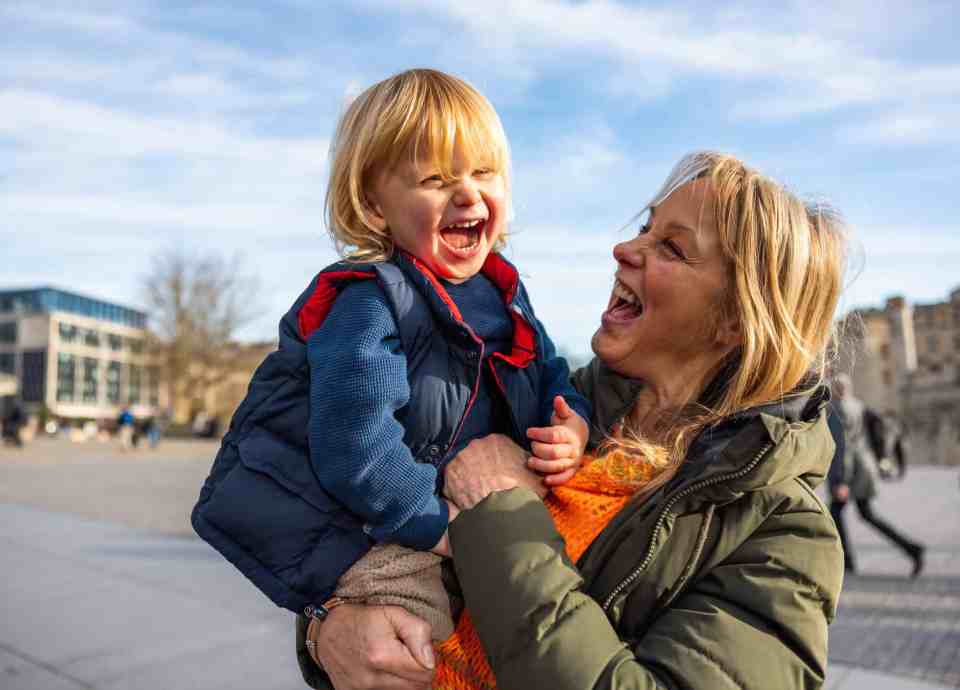 A smiling Grandmother holding her grandson on a sunny day.