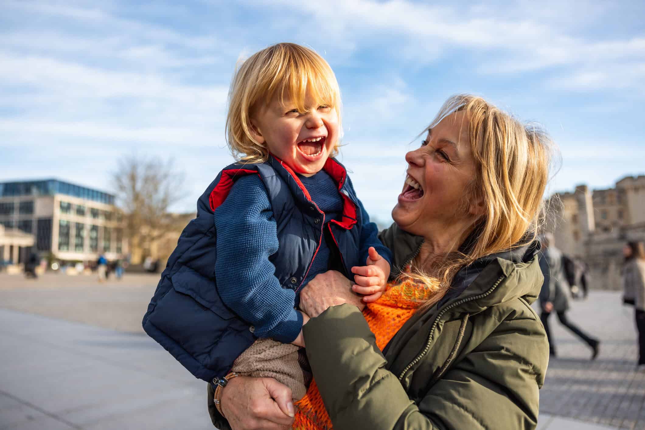 A smiling Grandmother holding her grandson on a sunny day.